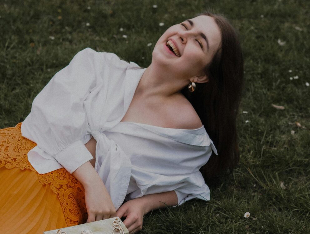 woman smiling in the grass after going to a dentist in Bethesda, MD